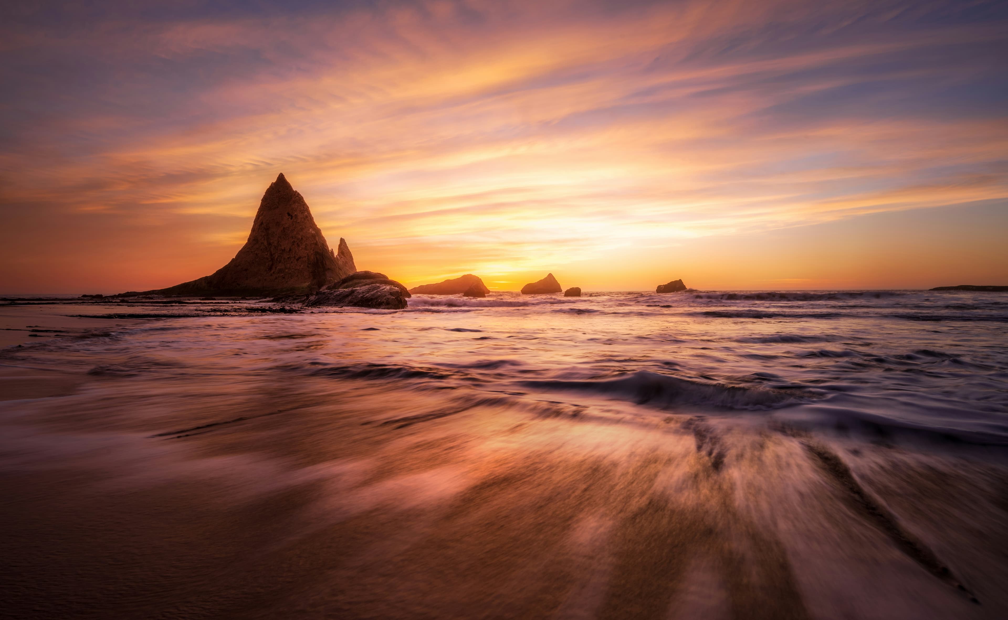 Golden-hour light over a rocky coastline as waves meet the shore